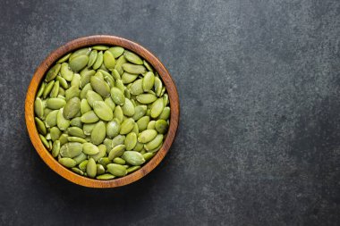 Siyah arka planda, tahta kasede balkabağı çekirdeklerinin üst görüntüsü