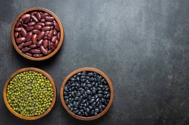 Yeşil fasulye, kırmızı böbrek fasulyesi ve siyah arka planda siyah kasede siyah böbrek fasulyesi.