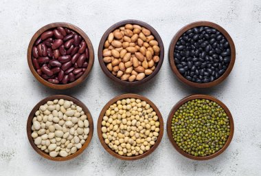 top view of red kidney beans, peanuts, black kidney beans, white kidney beans, soybean and mung beans in wooden bowls on white background. cereals collection clipart