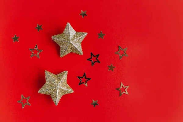 Golden sparkling stars on a red background. Flat lay. Place for text.