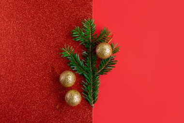 Parlak kırmızı arka planda güzel Noel süsleri ve ladin dalları. Düz yatıyordu. Metin için yer.