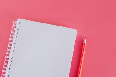 Notebook with a blank page and a pencil on pink background. Flat lay. Place for text.