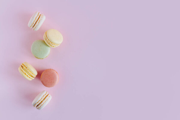 Tasty french macarons on a pink pastel background. Place for text. Flat lay.