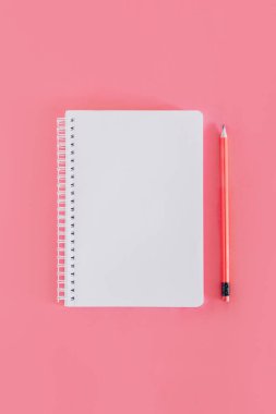 Notebook with a blank page and a pencil on pink background. Flat lay. Place for text.