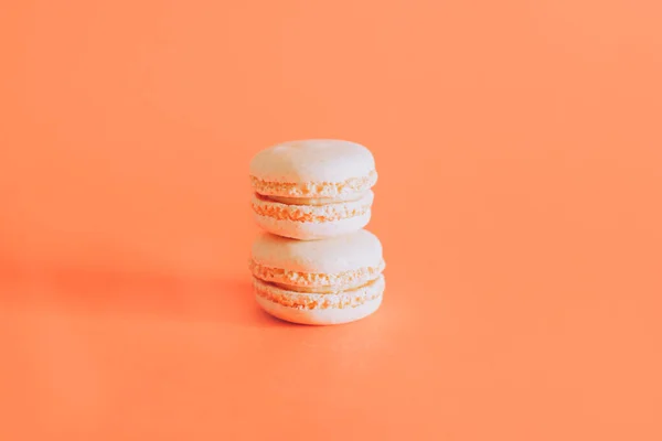 Tasty french macarons on a orange pastel background. Place for text.