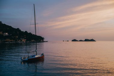 Hırvatistan 'ın Dubrovnik kenti yakınlarındaki denizde gün batımında güzel kırmızı bir tekne. Hırvatistan 'da seyahat hedefi.
