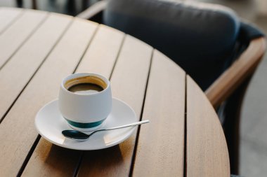 Kafedeki ahşap bir masada bir fincan sade kahve. Metin için yer.