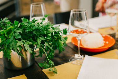 Öğle yemeği için bardaklar ve taze otlarla servis edilen masa. Seçici odak.