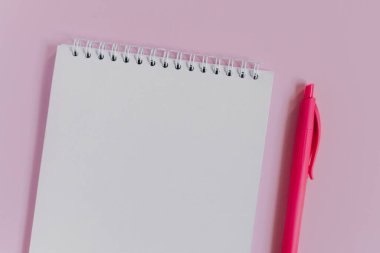 Boş sayfası ve pembe arka planı olan bir defter. Düz yatıyordu. Metin için yer.