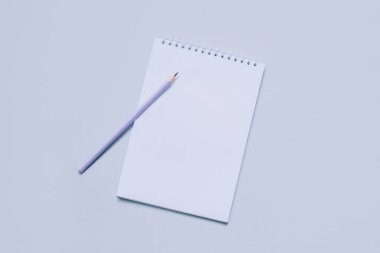 Açık mor arkaplanlı, boş sayfalı ve kalemli bir defter. Düz yatıyordu. Metin için yer.
