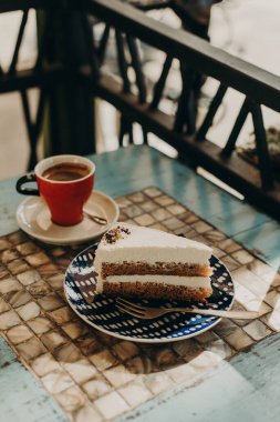 Tabakta nefis bir pasta ve kafede bir fincan kahve. Gün ışığı. Seçici odak.