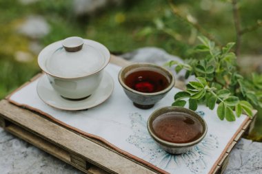 Geleneksel bir Çin çay setinin olduğu çay seremonisi sahnesi pürüzsüz, doğal bir ahşap çay tepsisinin üzerinde dinleniyor..