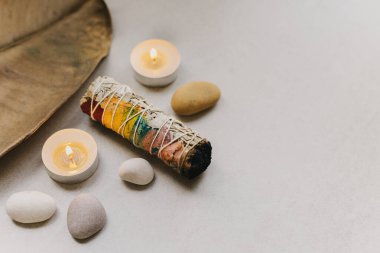 Meditasyon için taşlı beyaz adaçayı ve mum. Minimalizm. Sakin ve dikkatli ol. Metin için yer.