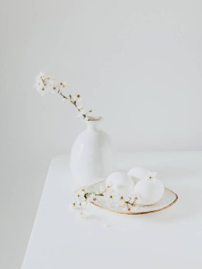 Vazoda güzel çiçek dalları ve beyaz arka planda yumurtalar. Bahar minimalist konsepti. Metin için yer.