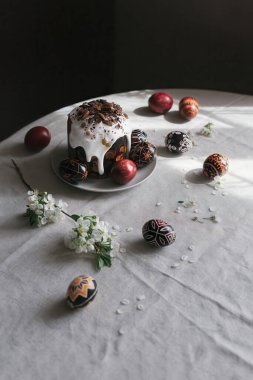 Geleneksel Ukrayna paskalya ekmeği Paska ve paskalya yumurtaları Pysanka siyah, kırmızı ve beyaz renklerde ve masada kiraz çiçekleri. Paskalya 'da hayat. Modern minimalizm.