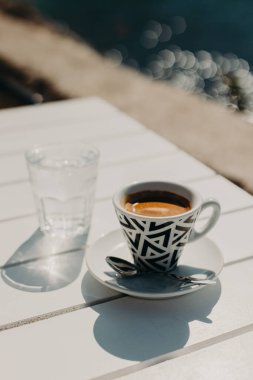 Güneşli bir sabahta bir sokak kafesinde bir fincan sade kahve ve bir bardak su. Seçici odaklanma. Metin için yer.