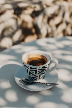 Seramik bir fincan sade kahve güneşli bir sabahta bir sokak kafesinde bir masanın üzerinde. Seçici odaklanma. Metin için yer.