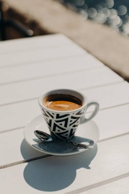 Güneşli bir sabahta masaya seramik bir fincan sade kahve. Seçici odaklanma. Metin için yer.