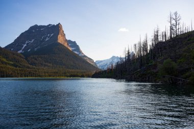 Montana 'daki Glacier Ulusal Parkı' ndaki Dusty Star Dağı bulutsuz bir yaz akşamı Saint Mary Gölü 'nden gün batımında görüldü.. 