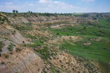 Theodore Roosevelt National Park of North Dakota, shown here during a summer day with cumulus clouds in the sky, is where the Great Plains meet the rugged Badlands. 