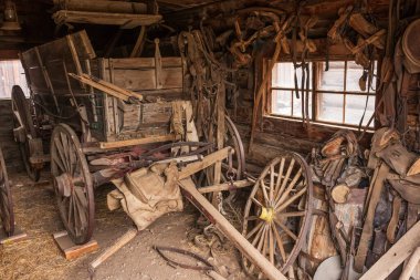 Cody, WY, USA - Jun 25, 2022: Old Trail Town is a tourist attraction with authentic frontier buildings from the late 1800's.  A garage with old wagon parts collects dust and dirt. 