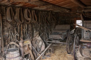 Cody, WY, USA - Jun 25, 2022: Old Trail Town is a tourist attraction with authentic frontier buildings from the late 1800's.  A garage with old wagon parts collects dust and dirt. 