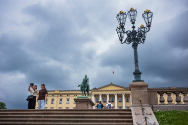 Oslo, Norveç, 20 Haziran 2023: Turistler fırtınalı bir günde Kraliyet Sarayı 'nı ziyaret ettiler. Burası monarşinin işlediği yerdir. Kral, Konsey 'e ve Kral ve Kraliçe' nin yaşadığı yere başkanlık eder..