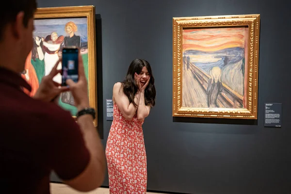 Oslo, Norveç, 20 Haziran 2023: Turistler Ulusal Galeride ünlü Edvard Munch kompozisyonu The Scream 'i gözlemlediler. Ziyaretçiler ünlü pozu taklit ederken fotoğraf çekiyorlar.. 