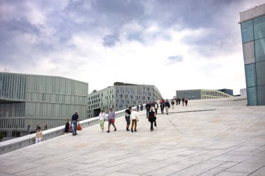 Oslo, Norveç, 19 Haziran 2023: Turistler, ziyaretçilere mermer kaplı çatısında yürüme olanağı sağlamak amacıyla 2008 yılında inşa edilen Oslo Opera Binası 'nı keşfediyorlar.. 