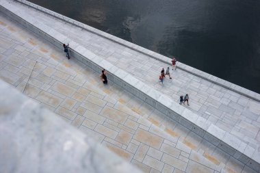 Oslo, Norveç, 19 Haziran 2023: Turistler, ziyaretçilere mermer kaplı çatısında yürüme olanağı sağlamak amacıyla 2008 yılında inşa edilen Oslo Opera Binası 'nı keşfediyorlar.. 