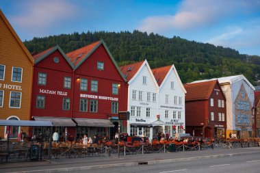 Bergen, Norveç - 23 Haziran 2023: Müşteriler, Vagen limanının doğu tarafında sıralanan bir dizi Hanseatik mirası ticari binası Bryggen 'ın dışındaki açık hava barında bir içeceğin keyfini çıkarıyorlar..