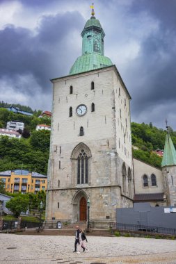 Bergen, Norveç, 22 Haziran 2023: Bergen Katedrali, kaldırım taşı caddelerinde yürüyen insanlarla birlikte bulutlu gökyüzü ile gösterilen, Bjorgvin Piskoposluğu ve Norveç Kilisesi 'nin piskoposluk merkezidir.. 