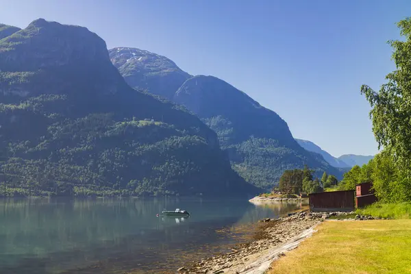 Krossen Dinlenme Tesisi 'nin Sogndal belediyesi yakınlarındaki Barsnesfjorden' in sakin sularında bir motorlu tekne yüzüyor..