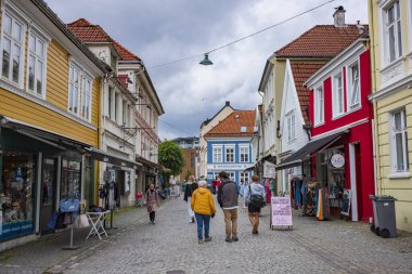 Bergen, Norveç, 22 Haziran 2023: Bir grup insan, Bergen şehir merkezindeki boş bir kaldırım taşı caddesinde yürür. Hollendergaten kaldırım taşı kaldırımlı yaya alışveriş caddesi.