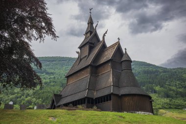 Hopperstad Stave Kilisesi. Norveç 'in Roysane şehrinde bulunan 1100' lü yıllara dayanan eski ahşap bir kilise. Bulutlu bir yaz gününde kasvetli fırtına bulutlarıyla fotoğraflanmış.. 