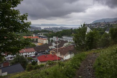 Norveç 'in Bergen şehrinde bulutlu bir yaz sabahı çekilmiş ev ve iş yerleri bir dağın kenarına inşa edilmiştir.. 