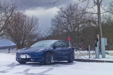 Trumansburg, New York, ABD - 14 Ocak 2023: Taughannock Falls Eyalet Parkı 'ndaki Şarj Noktası İstasyonu, Seviye 2' de Tesla Model 3 ücretlendiriliyor. gün.  
