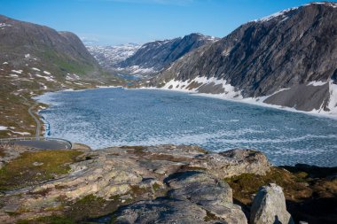 Kar, Norveç 'teki Jotunheimen Ulusal Parkı' ndaki Breiddalen Vadisi 'nde Geiranger yolu boyunca bir yaz günü boyunca zirve yaptı. Donmuş bir gölün havadan görünüşü. 