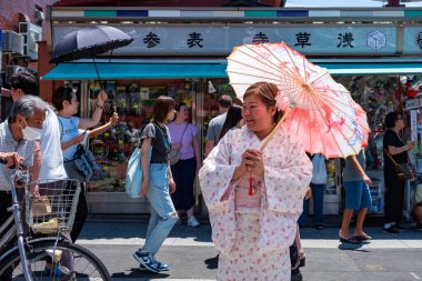 Tokyo, Japonya - 15 Haziran 2024: Bir kadın, Tokyo 'nun en eski tapınağı Senso-Ji Tapınağı yakınlarındaki Asakusa' nın en ünlü alışveriş caddesi olan Nakamise 'yi ziyaret ederken kimono giyiyor..  