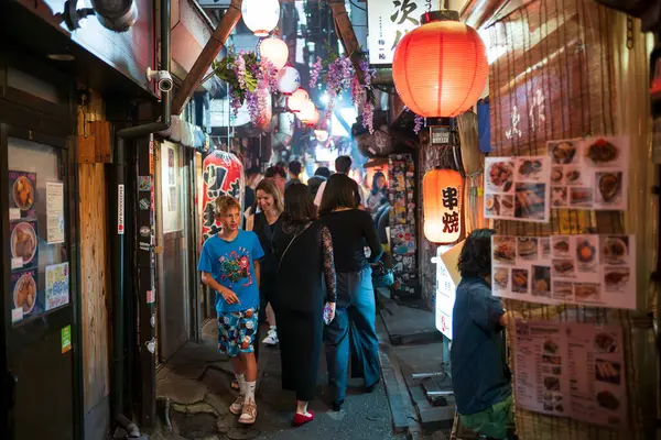 stock image Tokyo, Japan - Jun 15, 2024: Patrons walk the streets of Omoide Yokocho, a popular alleyway featuring food stalls serving  Japanese cuisine located in Shinjuku City and a popular tourist attraction.