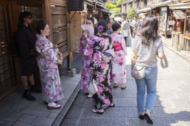 Kyoto, Japonya - 21 Haziran 2024: Kadınlar Kiyomizu Zaka 'yı ziyaret ederken kimono giyerler, dükkanlar, çay odaları ve yerel Kyoto tarzı mutfak ve hediyelik eşyalarla dolu bir alışveriş caddesi..