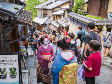 Kyoto, Japonya - 21 Haziran 2024: Kadınlar Kiyomizu Zaka 'yı ziyaret ederken kimono giyerler, dükkanlar, çay odaları ve yerel Kyoto tarzı mutfak ve hediyelik eşyalarla dolu bir alışveriş caddesi..