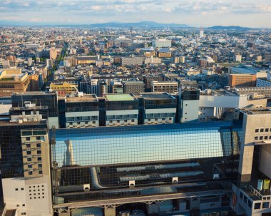 Kyoto, Japan - Jun 18, 2024: A view of the Kyoto train station featuring a glass roof and surrounding city seen from the tourist attraction, Nidec Kyoto Tower  during a late summer afternoon.  clipart