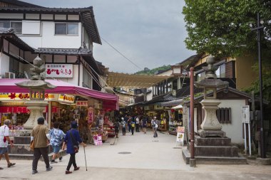 Itsukushima Jinja Tapınağı yakınlarındaki Miyajima Omotesand Alışveriş Sokağı 'nı gezen turistler, bulutlu bir günde.