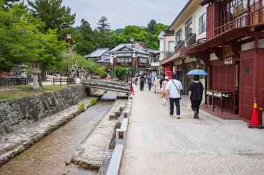 Itsukushima Jinja Tapınağı yakınlarındaki Miyajima Omotesand Alışveriş Sokağı 'nı gezen turistler, bulutlu bir günde.