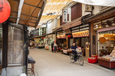 Itsukushima Jinja Tapınağı yakınlarındaki Miyajima Omotesand Alışveriş Sokağı 'nı gezen turistler, bulutlu bir günde.