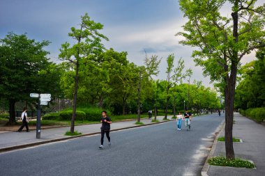 Osaka, Japonya, 23 Haziran 2024: Bir grup insan gün batımında Osaka Kalesi 'nin etrafını saran kaldırım yollarında yürüyor..