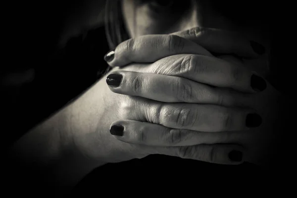 A closeup of a woman\'s hands in prayer in black and white
