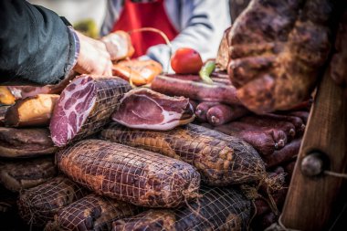 An outdoor stall with pieces of bacon and dried meat being sold