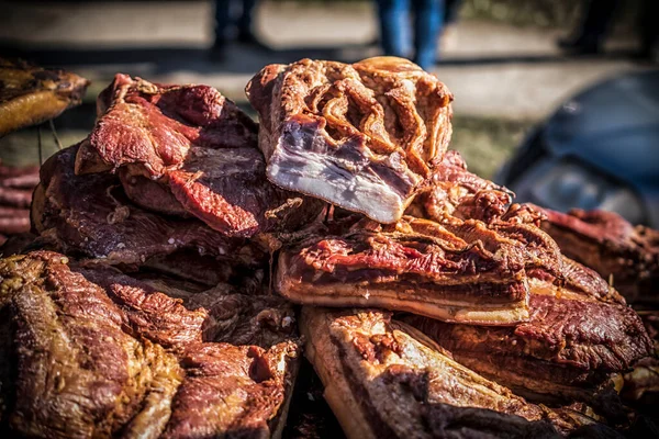 An outdoor stall with pieces of bacon and dried meat being sold